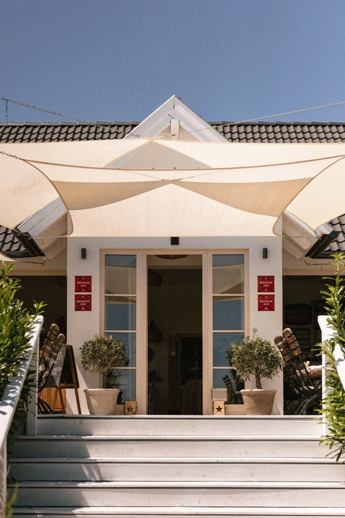 A Casa Christa Étterem bejárata napvitorlákkal és Michelin-elismerésekkel
